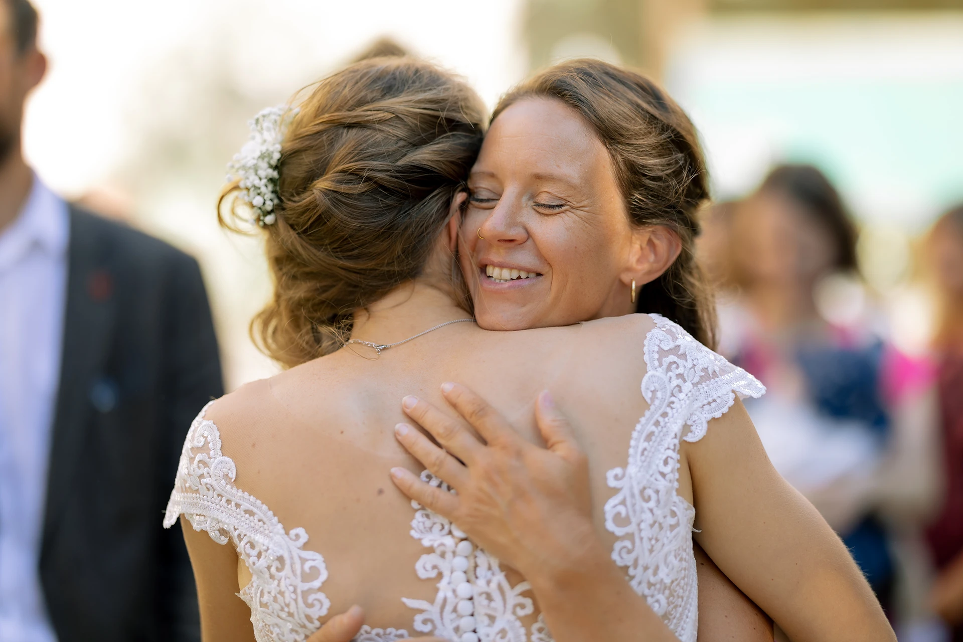 Die Braut wird von einer Freunding umarmt und gratuliert.